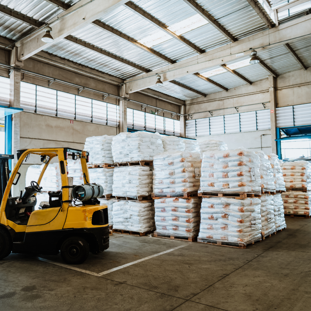 Forklift parked in warehouse beside stacked pallets of bagged materials