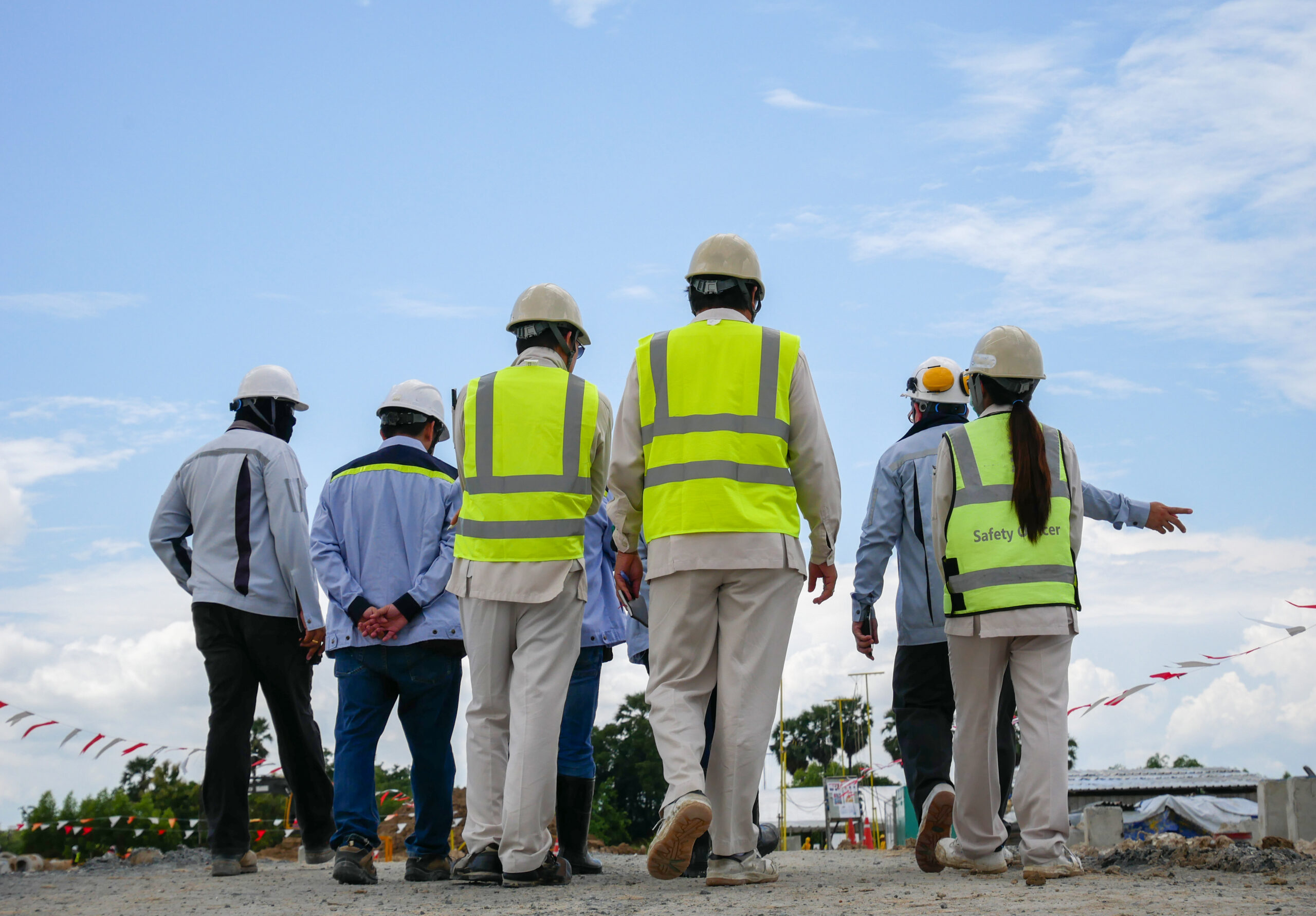 Group of construction workers in hard hats and safety vests walking on job site