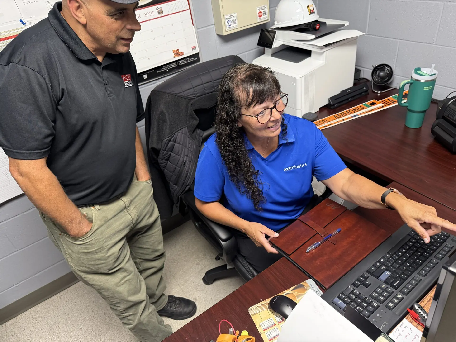 Two coworkers reviewing information on a computer in a small office workspace