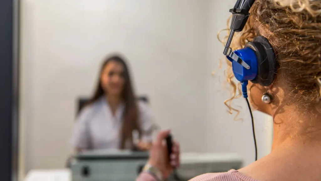 A woman is administering an occupational hearing test to another woman who has headphones on