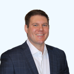 Smiling man in blazer and white shirt against plain background