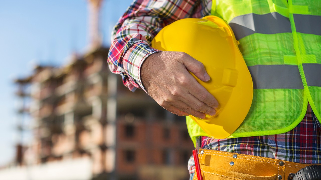 Close up of worker holding a hard hat on construction site