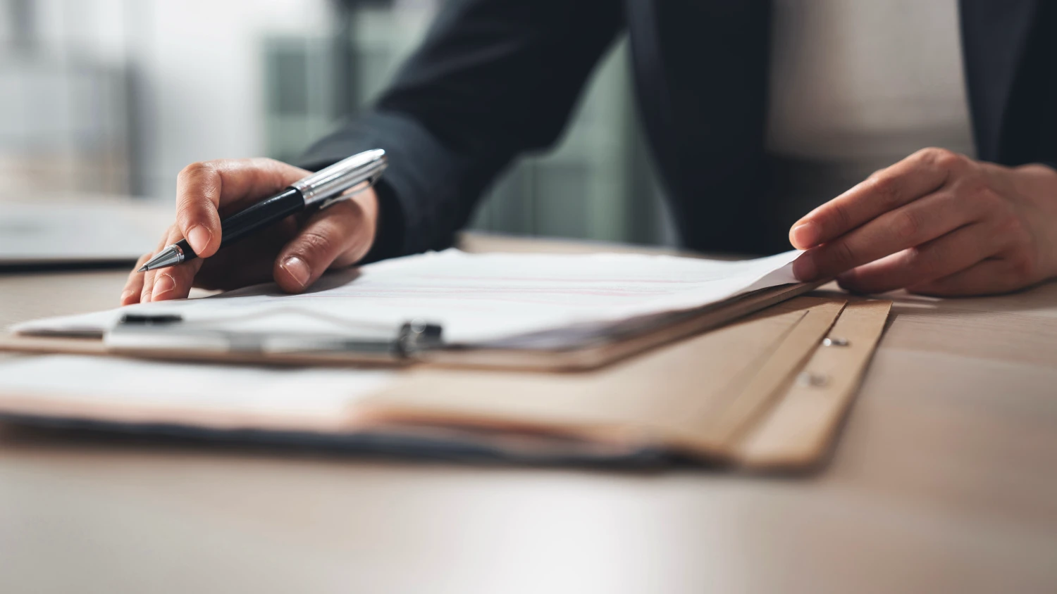 An administrator holding a pen while also sorting through paperwork regarding an injury management claim.